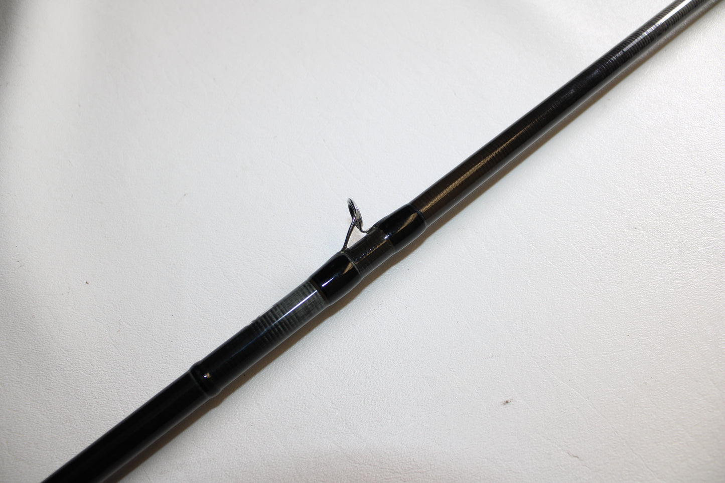 A close-up of a Daiwa Steez XT STZXT801MHRB used casting rod in good condition, featuring a black finish and single line guide, displayed on a white surface.