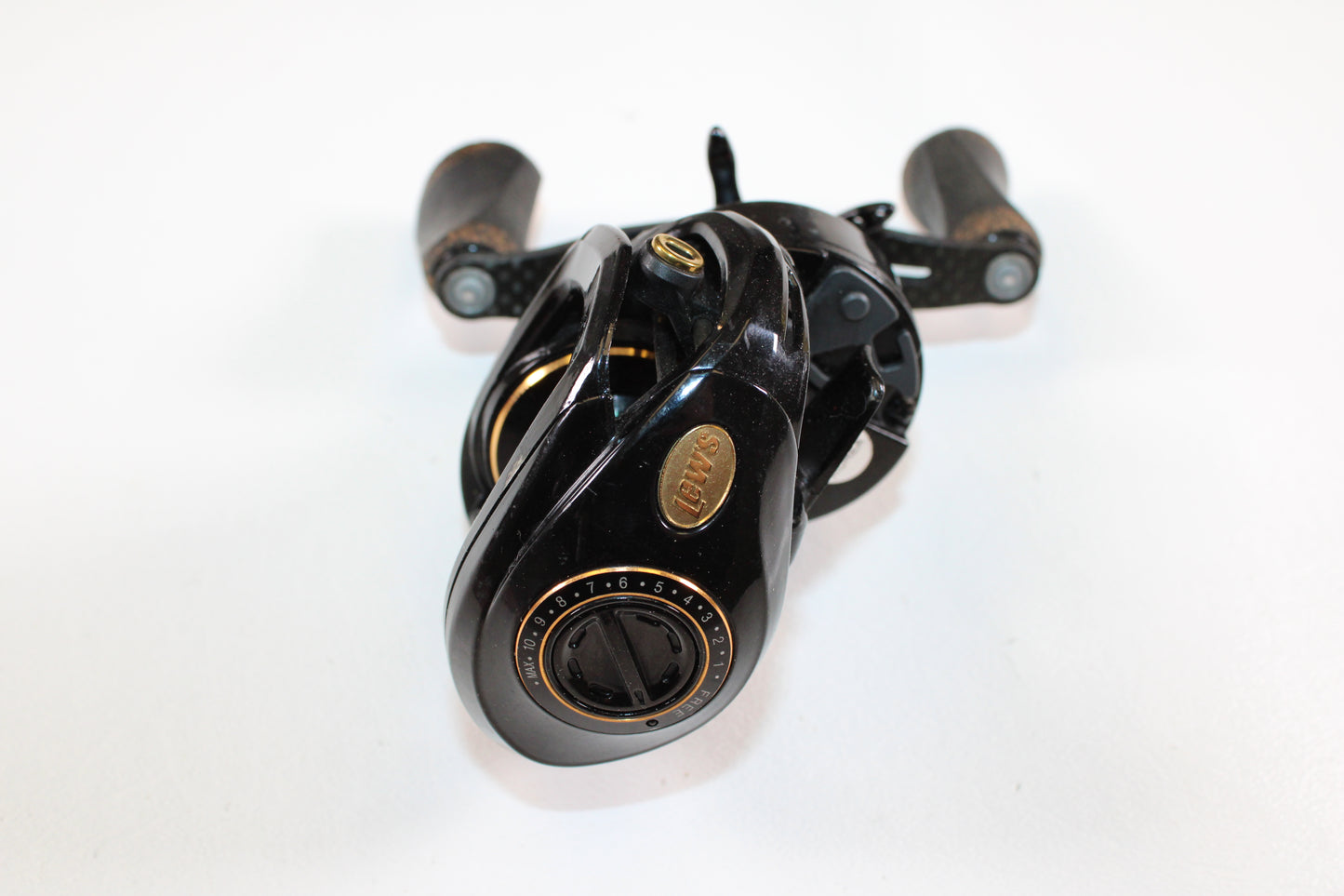 A Lew's Lite MgF LFS 7.5:1 LH Used Casting Reel in good condition—with black finish, gold accents, and wooden handle grips—is shown on a white background, ideal for Rod and Reel Trade-In or assessing Used Gear Condition.