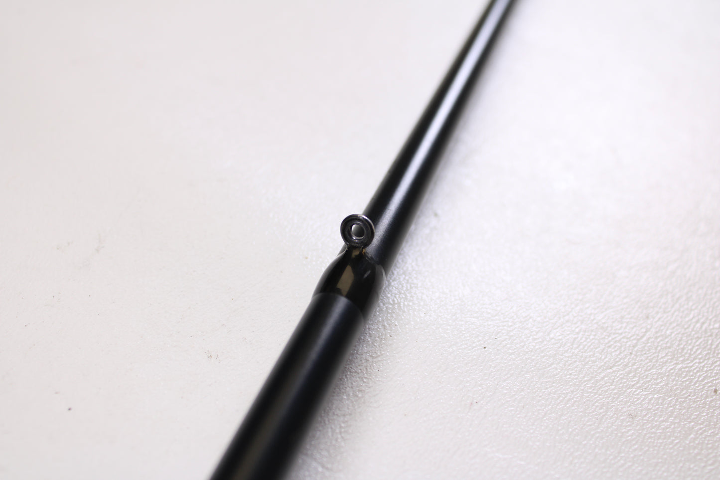 A close-up of a Fitzgerald PLF76MH 7'6" Medium Heavy Used Casting Rod in very good condition, highlighting a line guide against a white textured background.