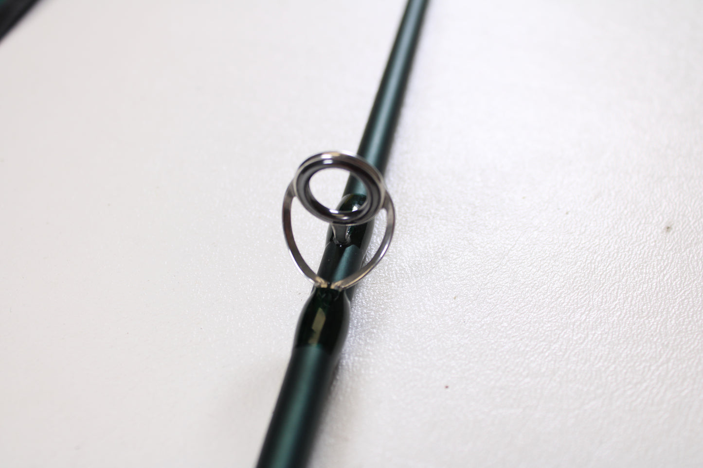 Close-up of the Douglas DXF Gen 1 6964 9'6" 6wt 4pc Used Fly Rod in excellent condition, highlighting its metal guide on a green rod. Ideal for those exploring our rod and reel trade-in program.