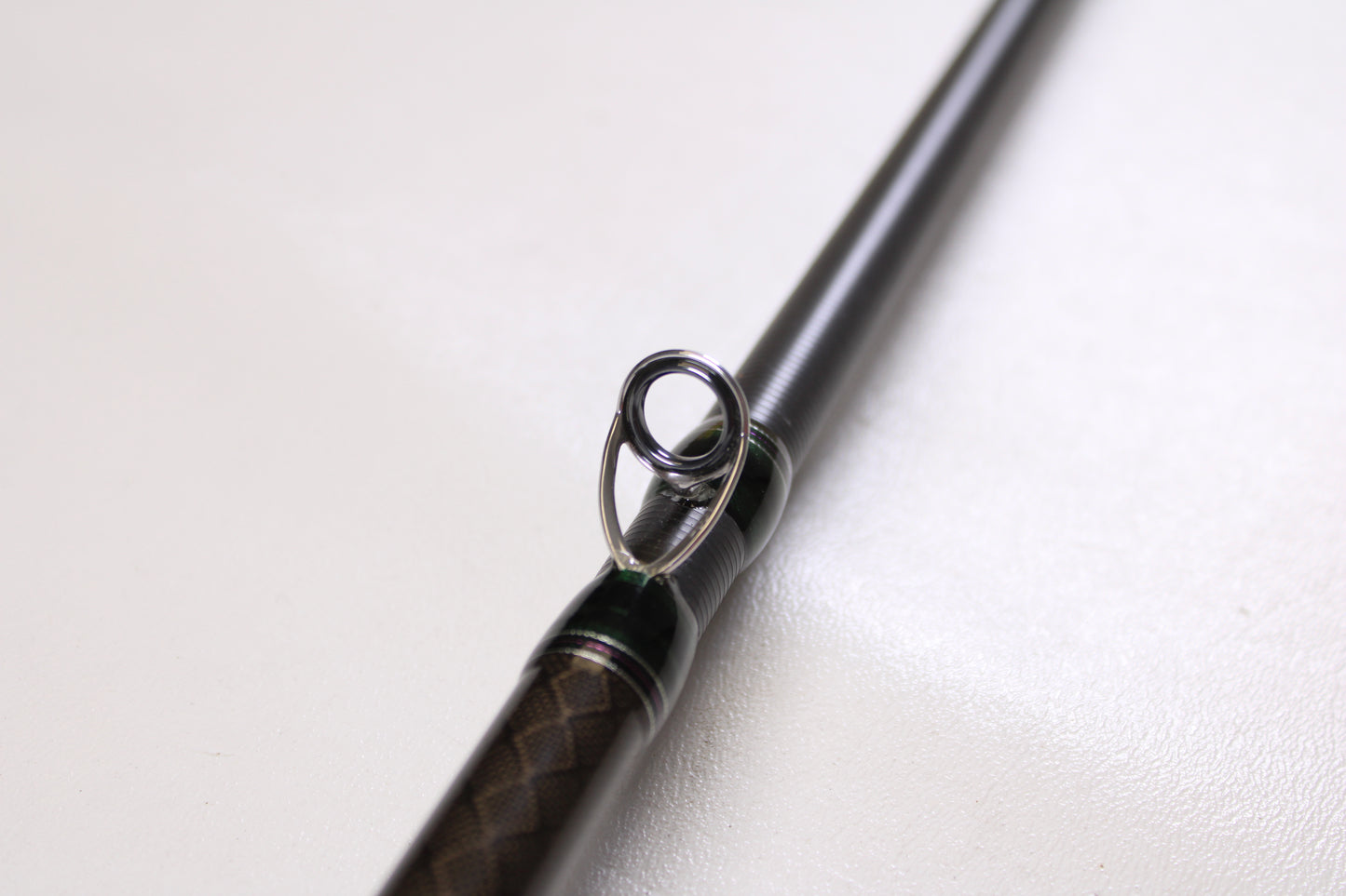 Close-up of a Megabass Orochi XX F6-711XXG Launcher 7'11" used casting rod in excellent condition, highlighting the metal guide ring and textured brown and black handle. Great option for our rod and reel trade-in upgrade program.