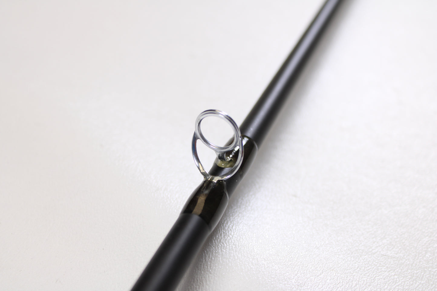 Close-up of a Temple Fork TFO Tactical Bass TACMBR734-1 7'3" Medium Used Casting Rod in excellent condition, showing the shiny metal guide on a black rod—ideal for those considering our rod and reel trade-in program.
