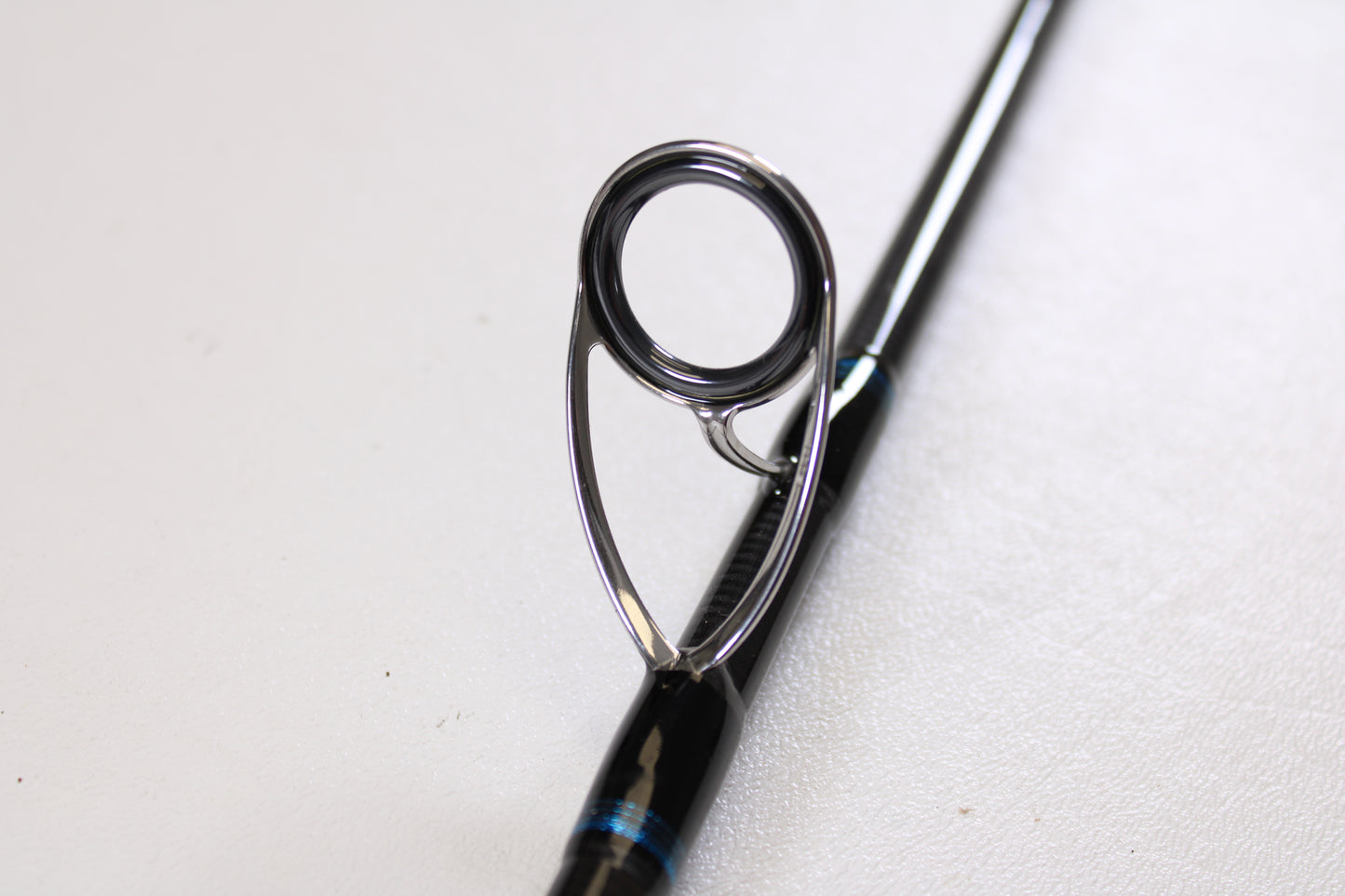 Close-up of the Tsunami Airwave Elite TSAWESS762LT 7'6" used spinning rod's guide, featuring a sturdy metal ring and frame on its black rod—ideal for anyone shopping quality pre-owned fishing gear.