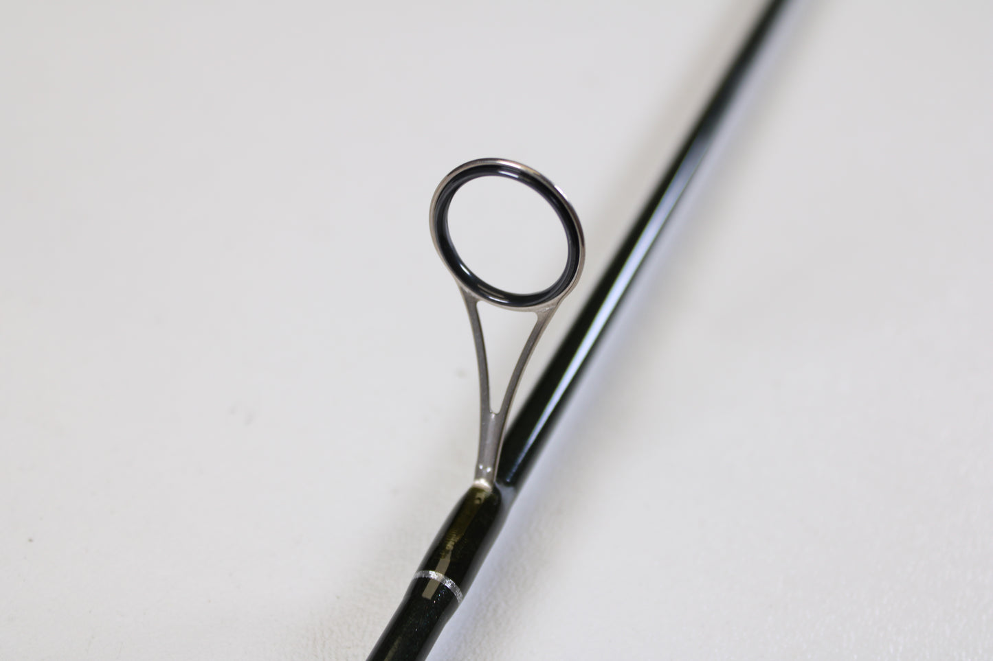 A close-up of the St. Croix Legend Elite Panfish LEP69LF 6'9" Light used spinning rod highlights a guide ring on its glossy black surface—promoting our Rod and Reel Trade-In Program: turn your used gear into store credit. Shot on a plain white background.