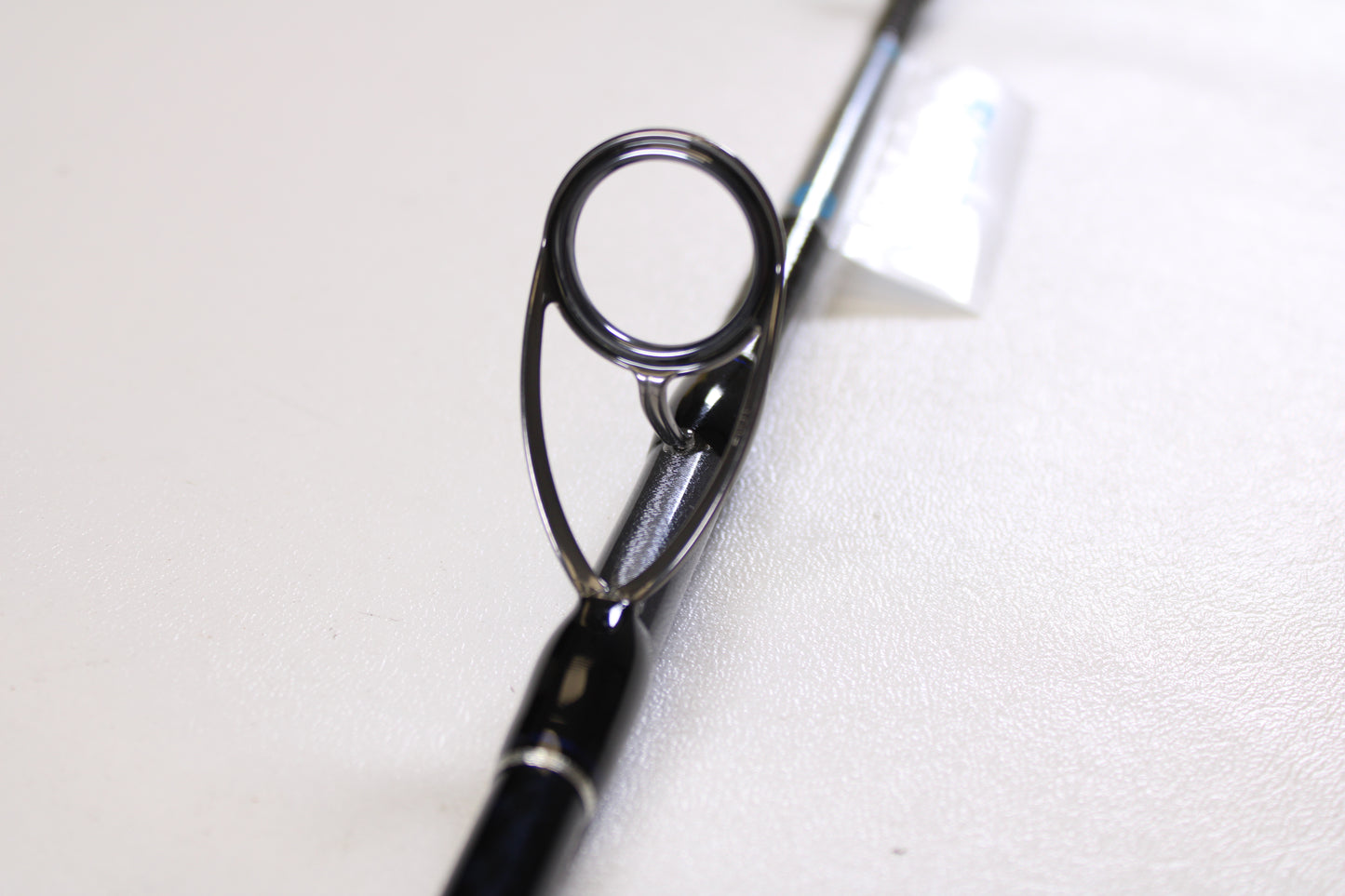 Close-up of a Shimano Terez BW TZBWS72MSBA 7'2" Medium Used Casting Rod in mint condition, highlighting the guide ring on its sleek black finish against a white background. Great option if you're considering an upgrade with our trade-in program.