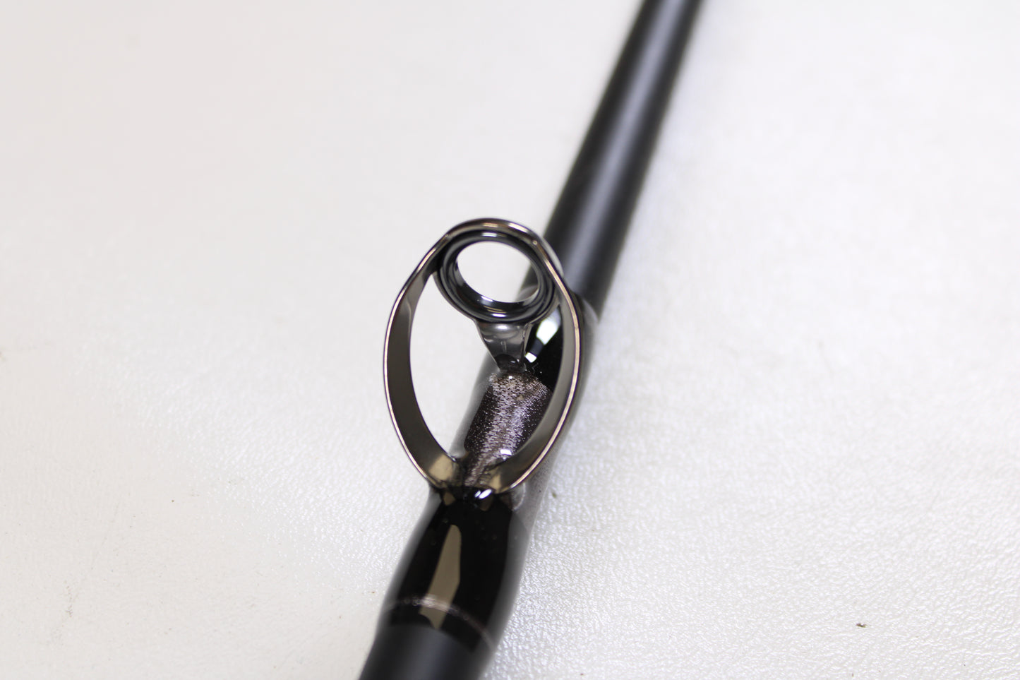 Close-up of a G. Loomis IMX-PRO Offshore 96-50 8'0" Heavy Used Casting Rod in mint condition, showing the guide ring on a black rod. Perfect for our rod and reel trade-in program. White background highlights G. Loomis quality.