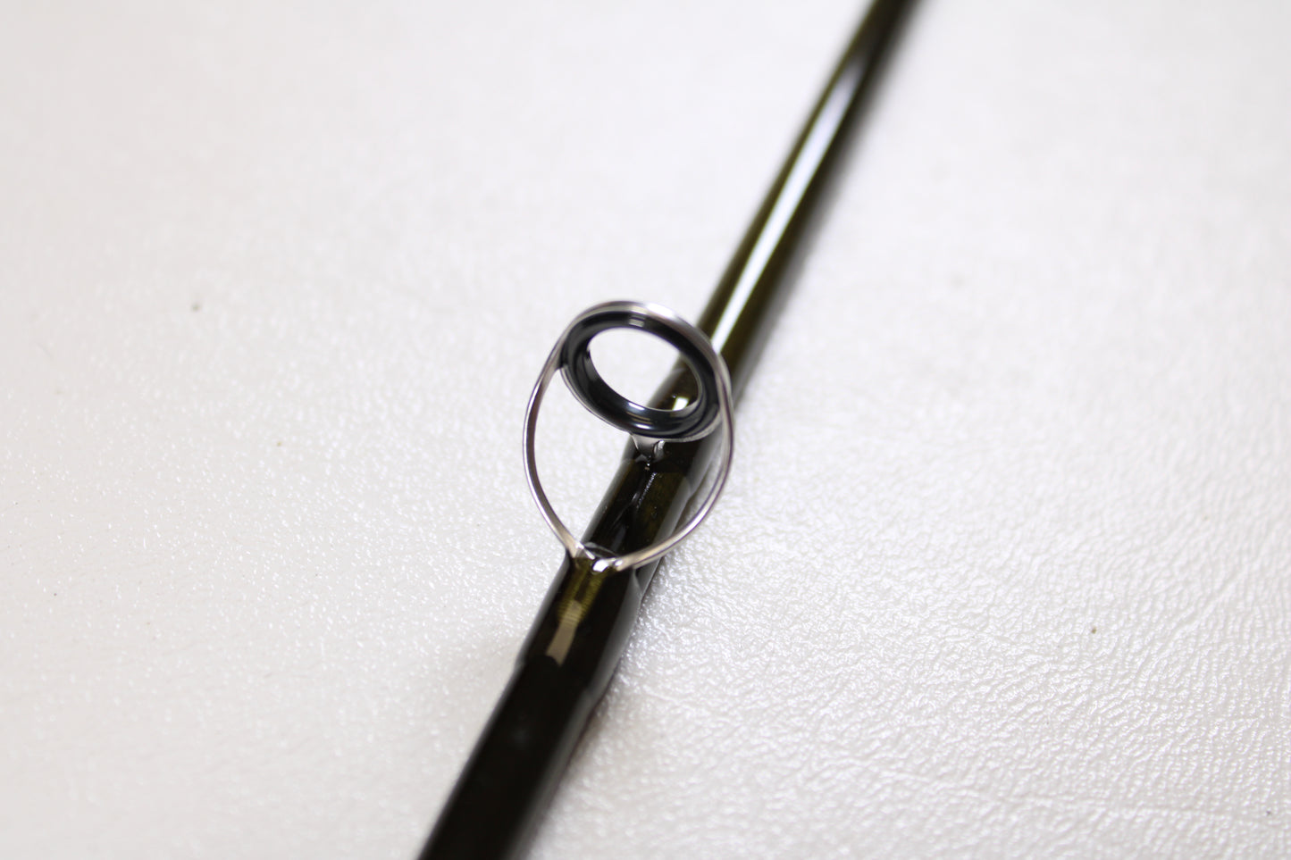 Close-up of the G. Loomis IMX-PRO Creek Fly Rod 279-4 7'9" #2 guide ring on a dark rod—ideal for anglers looking to trade in used gear like this mint-condition fly rod for store credit through our Rod and Reel Trade-In Program.