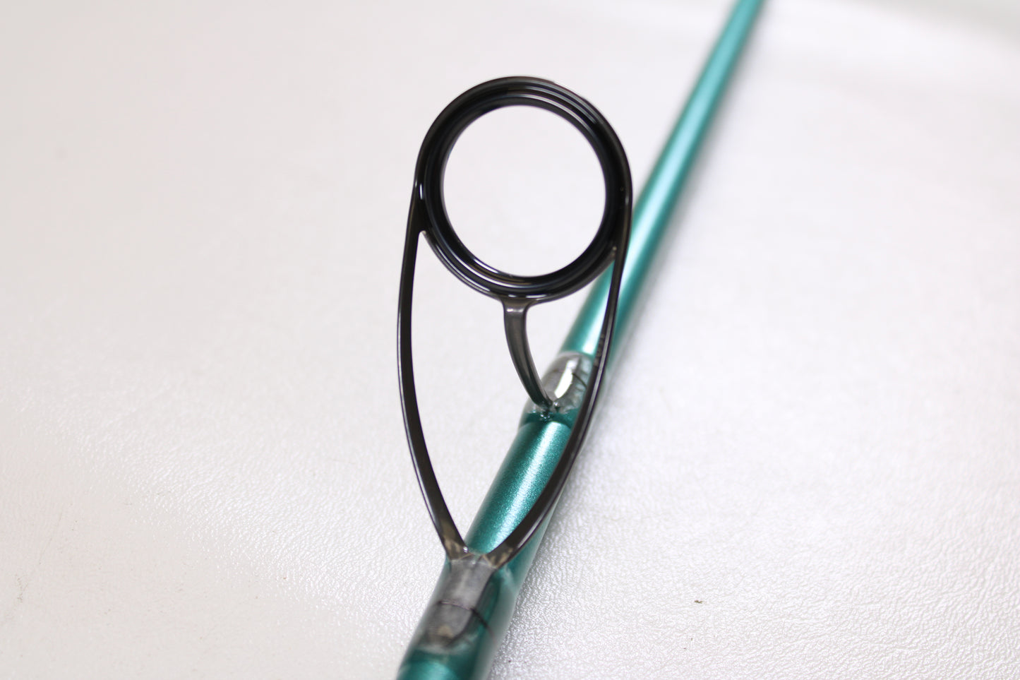 Close-up of a St. Croix Avid Inshore ASIS70HMF 7'0" Heavy Used Spinning Rod in mint condition, highlighting the metallic guide on a teal rod—ideal for those interested in premium used gear or our trade-in program.