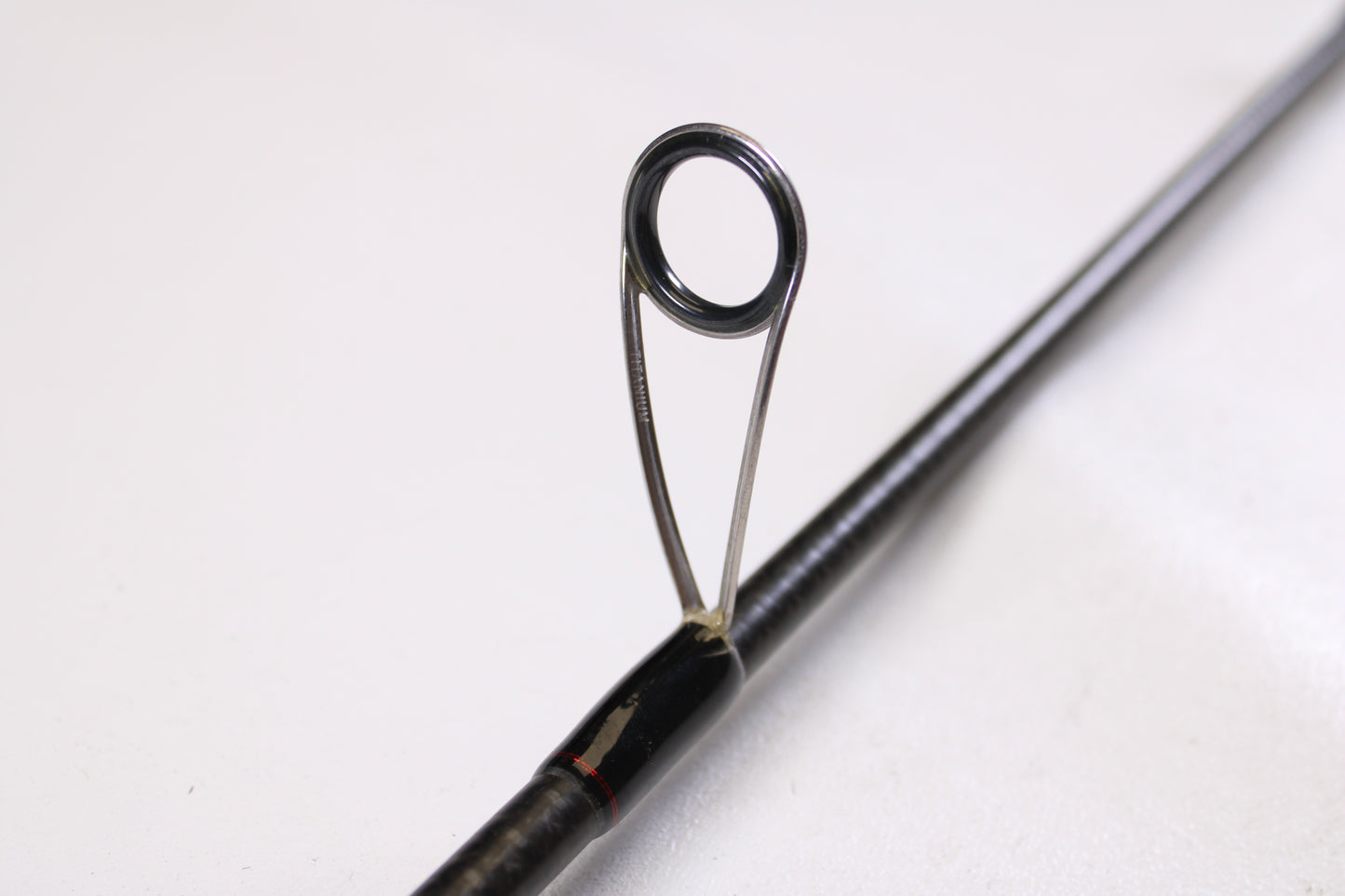 Close-up of a metal rod guide on the Abu Garcia Fantasista Regista FNRS70-5 7'0" Medium Used Spinning Rod in very good condition, perfect for anglers upgrading or shopping quality used gear. Plain white background.