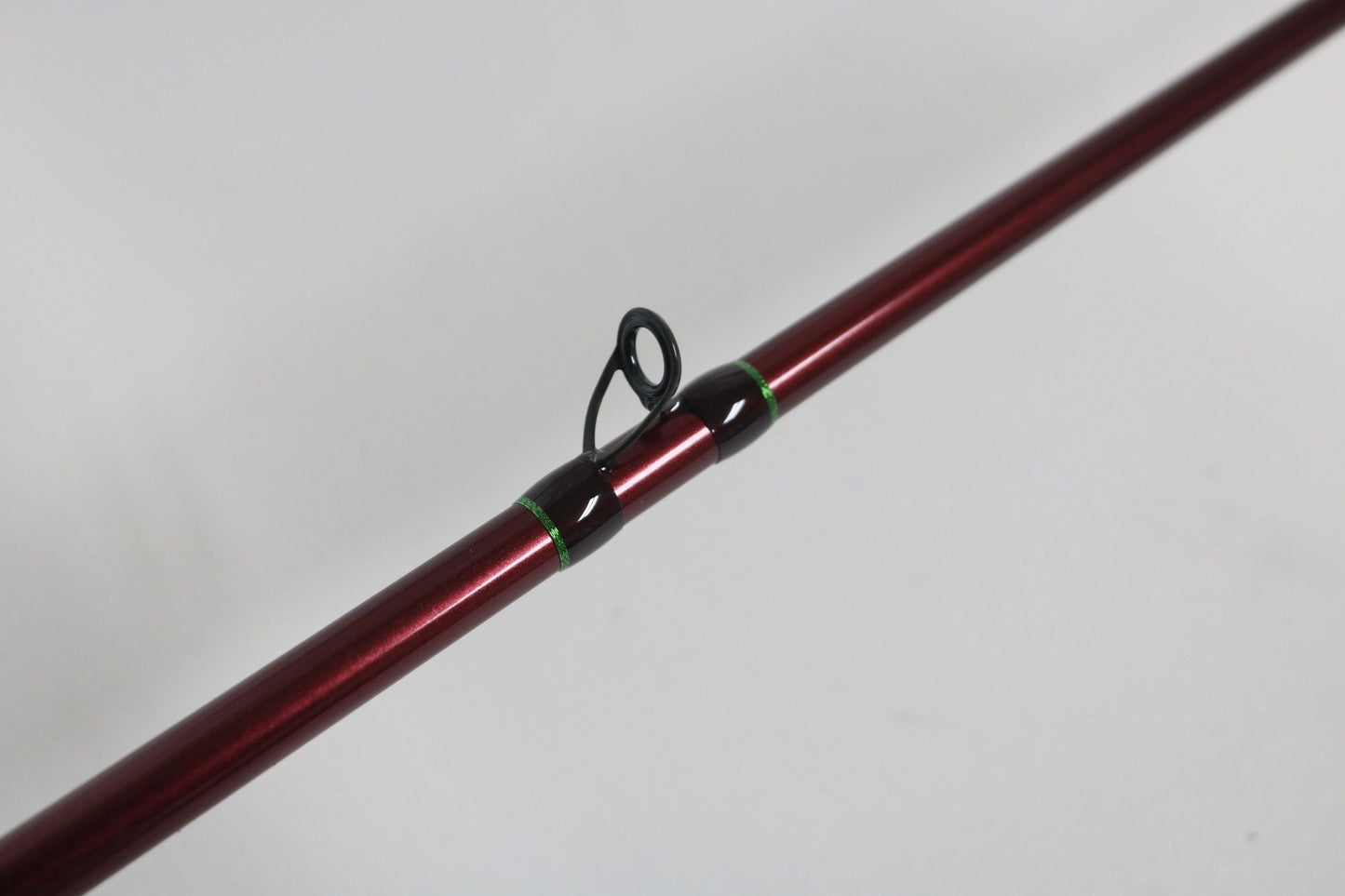 A close-up of the G. Loomis IMX PRO 862C BJR 7’2” Medium Used Casting Rod in mint condition, showing its red finish and metal line guide against a plain white background.
