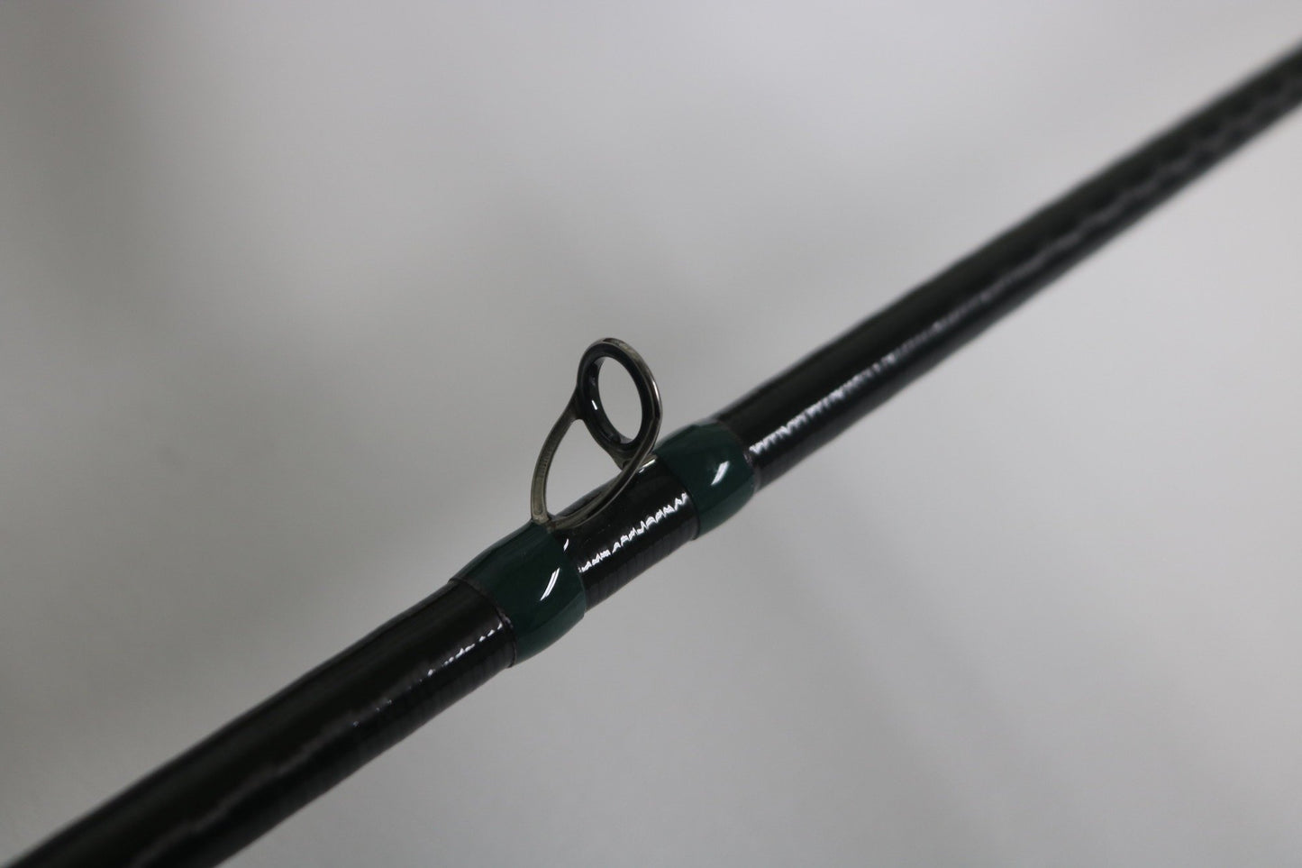 Close-up of a G. Loomis Conquest CNQ 904C MBR 7'6" Heavy Used Casting Rod in very good condition, showing a single metal guide wrapped with green thread—ideal for those upgrading gear through the Rod and Reel Trade-In Program.