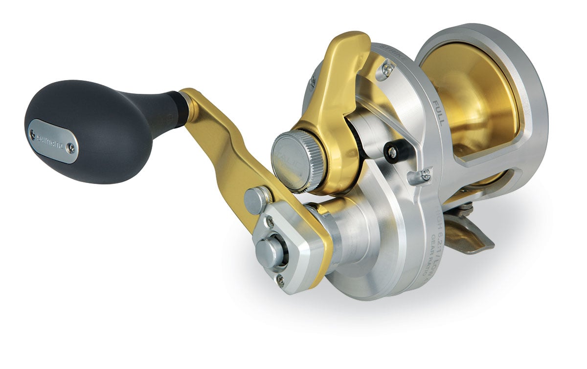 The Shimano Talica TAC8II 2 Speed Lever Drag Reel, shown in silver and gold with a black handle, features a sturdy crank and detailed metalwork, making it ideal for heavy-duty or saltwater fishing.