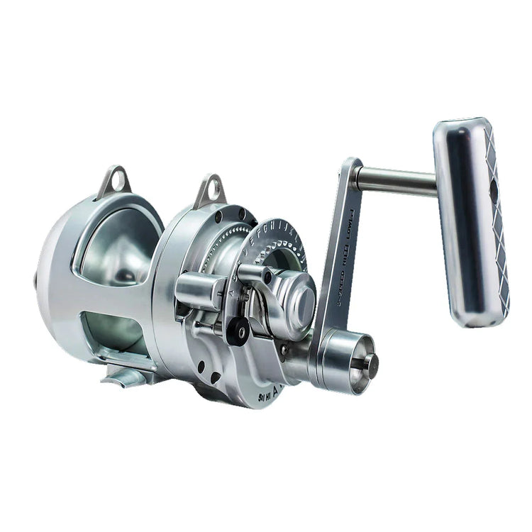 A silver fishing reel with a crank handle is shown against a white background. The reel has a modern design with multiple components visible.