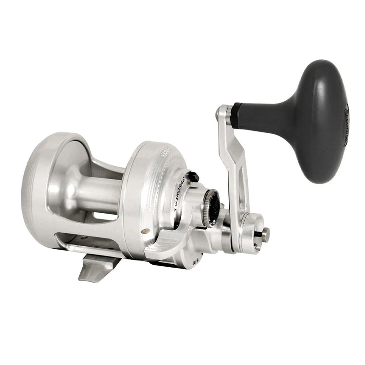 A silver fishing reel with a large handle and visible gears, designed for deep sea or big game fishing. The spool and frame are metal, giving it a durable appearance.