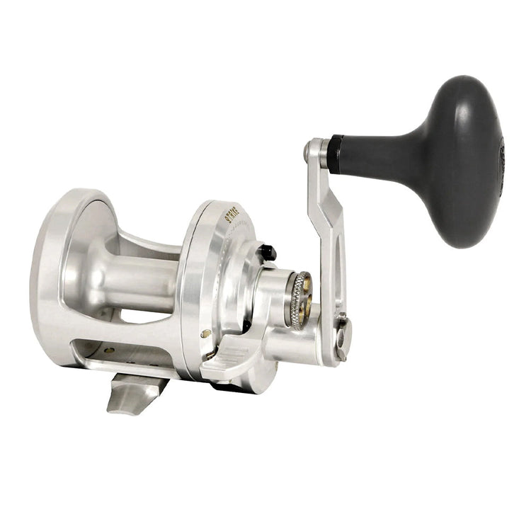 Silver fishing reel with a black handle, showing intricate gear details and a sturdy frame. The reel is designed for strength and durability, suitable for heavy-duty fishing.