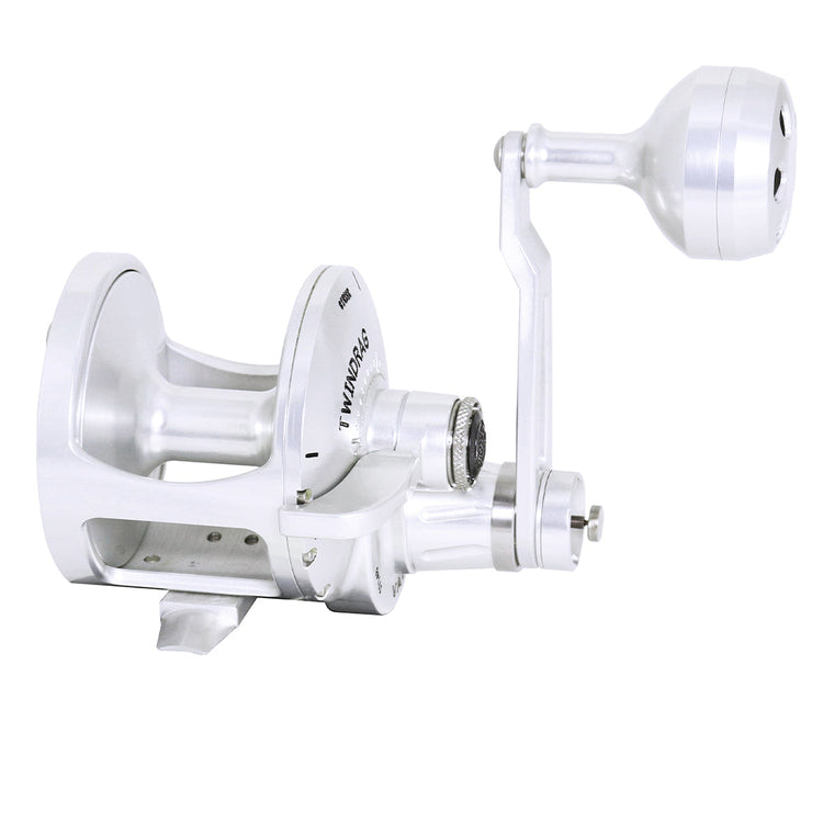 A sleek silver metallic fishing reel with a large handle, showcasing a modern and polished design, isolated on a white background.
