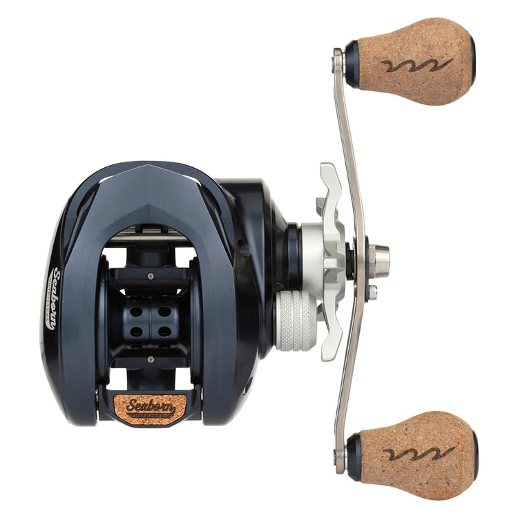 Top view of a black and silver baitcasting fishing reel with cork handle grips on a metal crank. The reel features intricate detailing and branding on its body, with a modern design.