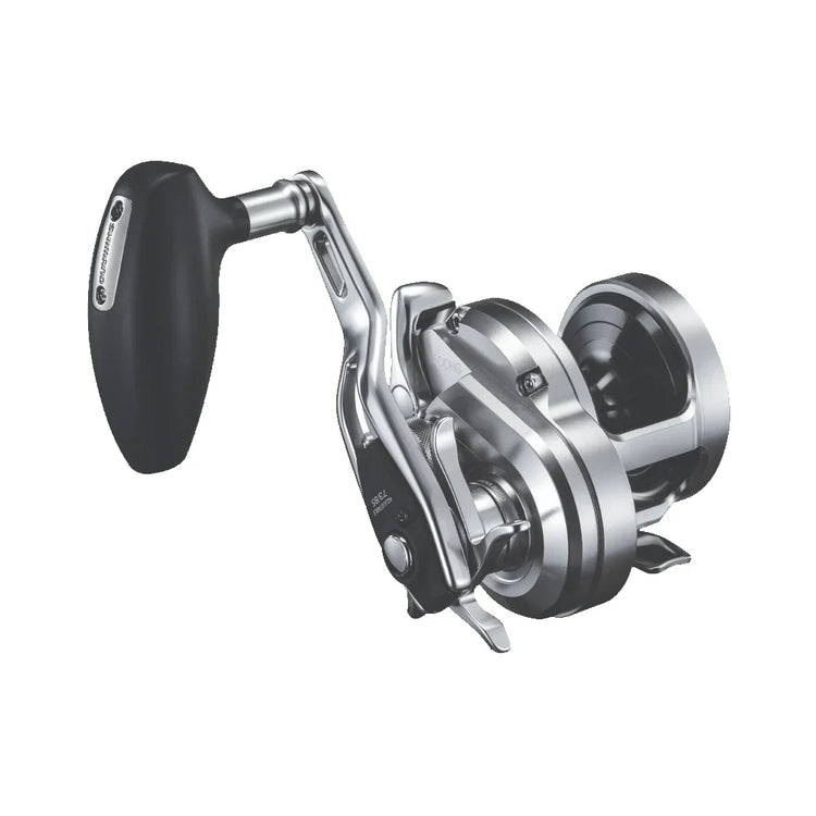 Close-up of a silver and black fishing reel with a large handle. The sleek, metallic design features a prominent gear and spool mechanism, showcasing its functionality and precision for fishing enthusiasts.