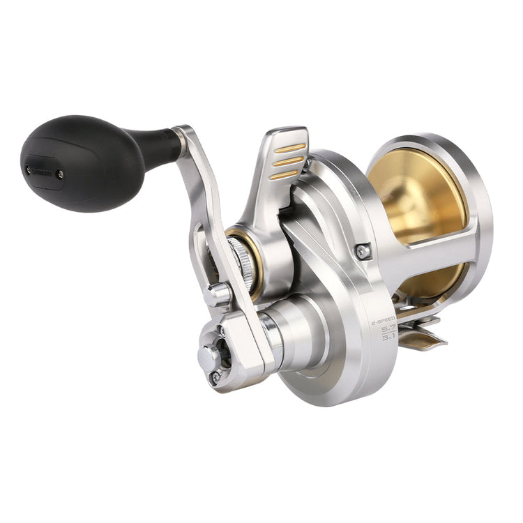 A silver and gold fishing reel with a black handle, featuring a robust design and intricate metal components.