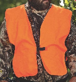 A person wearing a camouflage outfit with an Allen Safety Vest Blazer Orange Youth from americanlegacyfishing stands outdoors.