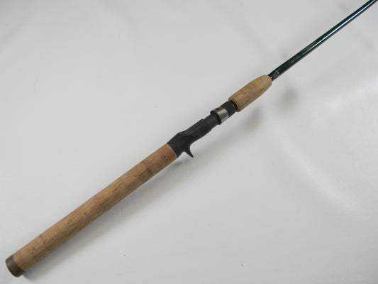 The St. Croix Tidemaster TIC66HF 6'6" Heavy Used Casting Rod in excellent condition, featuring a black finish with a cork handle and reel seat, rests diagonally on a white surface—ideal for enthusiasts upgrading through our Trade-In Program or earning Store Credit with Used Gear.