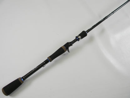 The Okuma TCS TCS-C-701MH 7'0" Medium Heavy rod, featuring a black design with a cork handle and blue accents, is displayed on a white surface. Its sleek build offers comfort and style, ideal for upgrading in our Rod and Reel Trade-In Program if you have used gear.