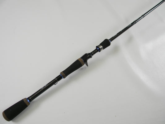 The Okuma TCS TCS-C-701MH 7'0" Medium Heavy rod, featuring a black design with a cork handle and blue accents, is displayed on a white surface. Its sleek build offers comfort and style, ideal for upgrading in our Rod and Reel Trade-In Program if you have used gear.