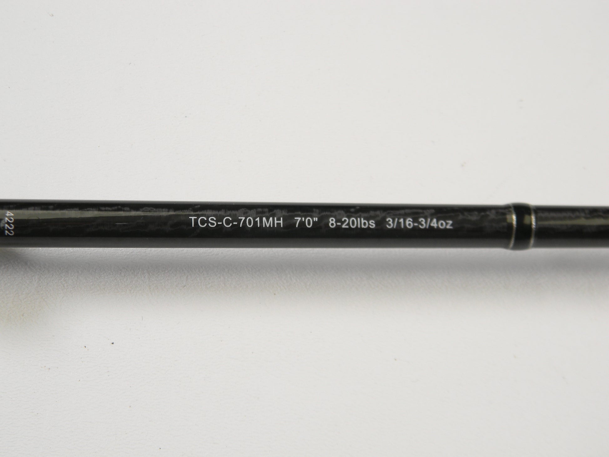 Close-up of an Okuma TCS TCS-C-701MH 7'0" Medium Heavy casting rod, showing specs "8-20lbs 3/16-3/4oz" printed in white on black. It's ideal for our Rod and Reel Trade-In Program. The rod is set against a plain white background.