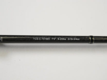 Close-up of an Okuma TCS TCS-C-701MH 7'0" Medium Heavy casting rod, showing specs "8-20lbs 3/16-3/4oz" printed in white on black. It's ideal for our Rod and Reel Trade-In Program. The rod is set against a plain white background.