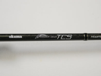 Close-up of a black fishing rod with "Okuma TCS TCS-C-701MH 7'0" Medium Heavy" printed on it against a white background. Ideal for upgrading through our Rod and Reel Trade-In Program, offering store credit on used gear.