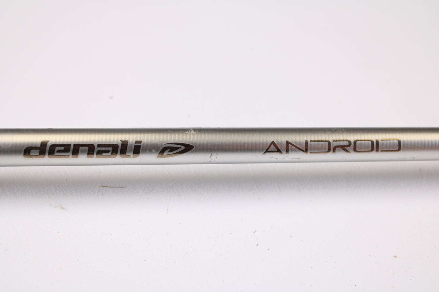 A close-up of a Denali Android ADC744WJ 7'4" Heavy used casting rod in good condition, showing "Denali" and "ANDROID" with a logo engraved on the metallic rod, set against a white background—ideal for our rod and reel trade-in program.