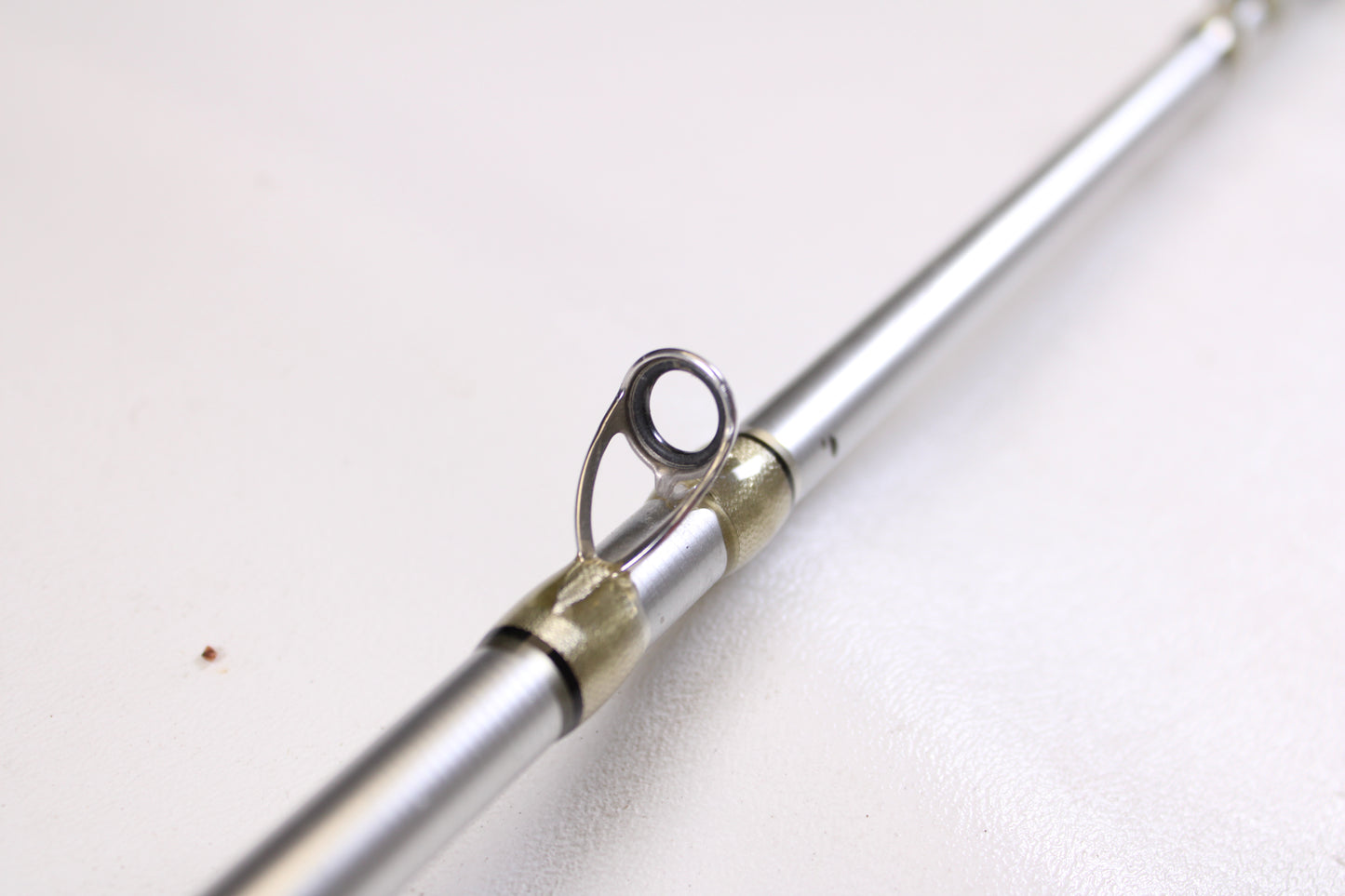 Close-up of the Denali Android ADC744WJ 7'4" Heavy used casting rod's metallic guide against a white background—ideal for shoppers seeking quality pre-owned Denali gear.