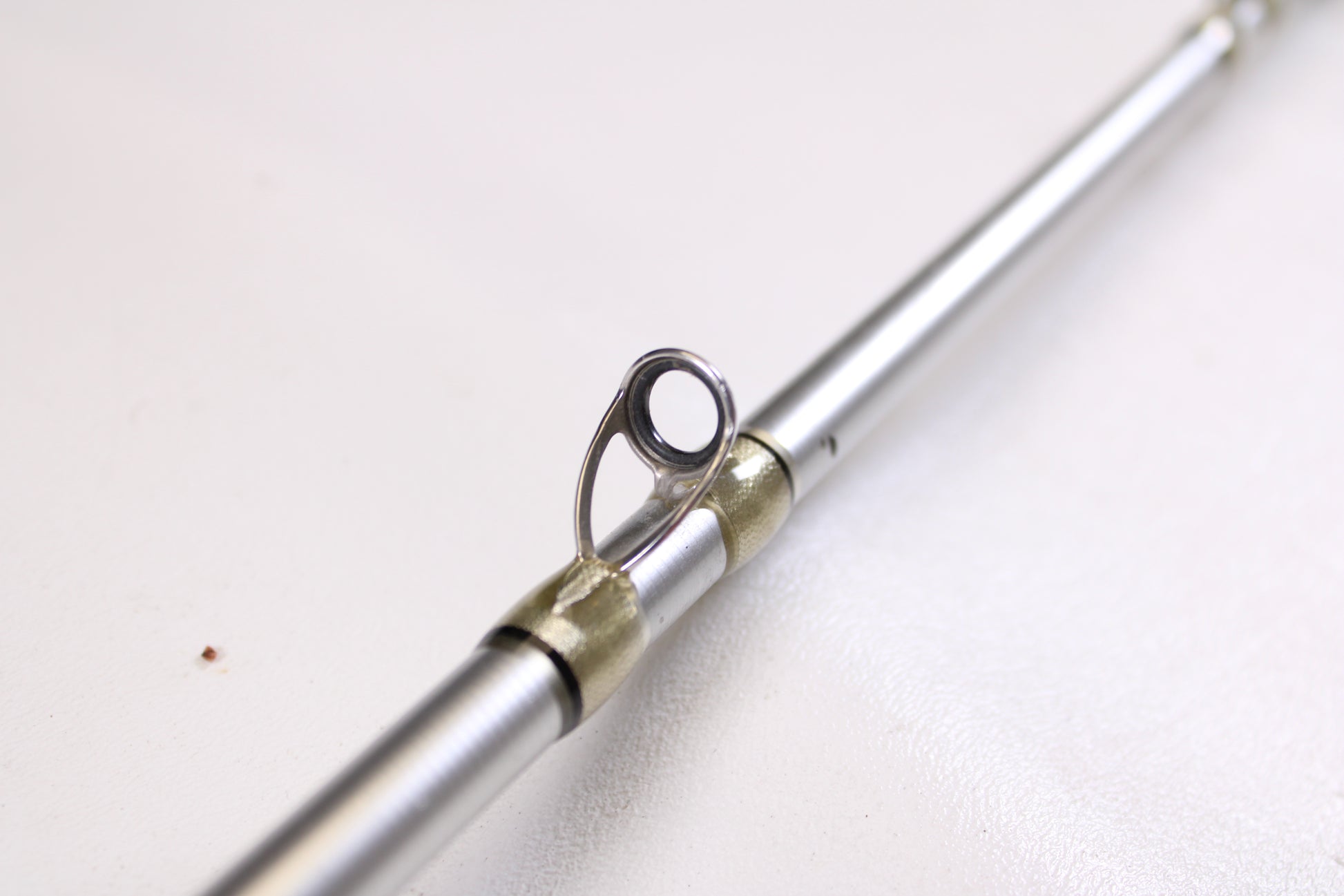 Close-up of the Denali Android ADC744WJ 7'4" Heavy used casting rod's metallic guide against a white background—ideal for shoppers seeking quality pre-owned Denali gear.