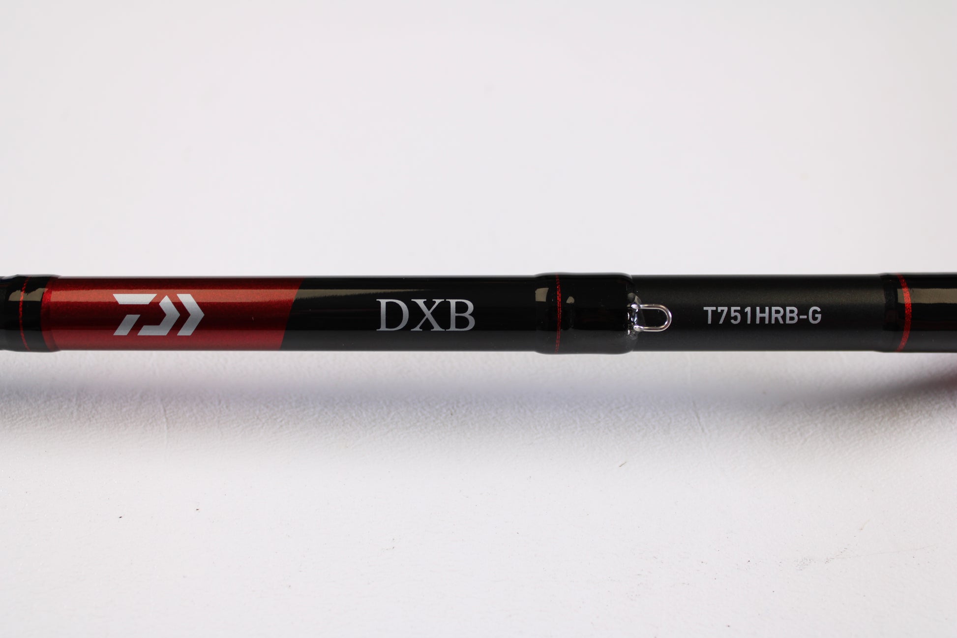 Close-up of a Daiwa DXB DXBT751HRB-G 7'5" Heavy Glass Used Casting Rod in excellent condition, black and red with branding visible, on a white background. Ideal for anglers upgrading via our rod and reel trade-in program for store credit.