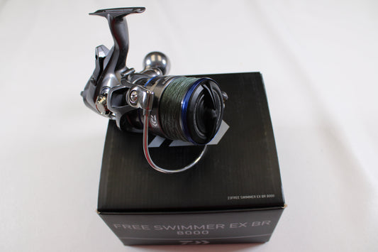 A Daiwa Free Swimmer EX BR 8000 Used Spinning Reel in excellent condition, spooled with green line and mounted on a black box, can be traded in for store credit through our rod and reel trade-in program. Box features clear branding; background is plain white.