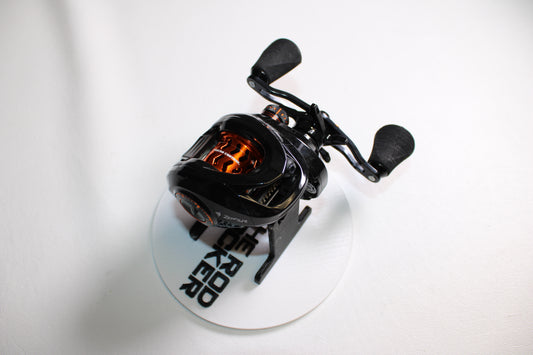A KastKing Zephyr 7.2:1 Gear Ratio LH casting reel, in excellent used condition, is displayed on a white circular stand labeled "RED ROCKET", with a plain white background.