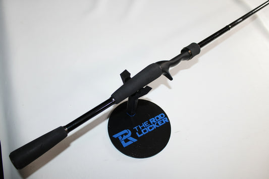 A Daiwa Steez XT STZXT801HFB used casting rod in good condition is displayed on a round black stand labeled “The Rod Locker” in blue and white, set against a white background.