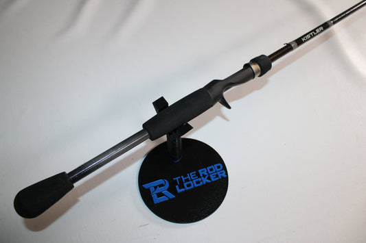 A Kistler Graphite GR705H 7'0" Heavy used casting rod in very good condition is displayed on a round black stand with blue text reading "The Rod Locker," set against a plain white background.