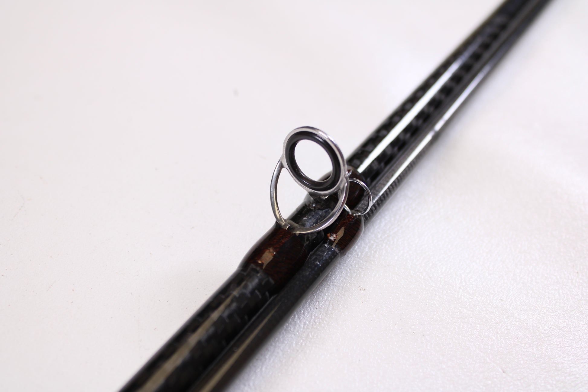Close-up of an American Tackle Matrix 10'6" 10WT 2 Piece Used Fly Rod in excellent condition—black carbon-fiber shaft and metal guide shown. Trade in your used gear for store credit through our Rod and Reel Trade-In Program!.
