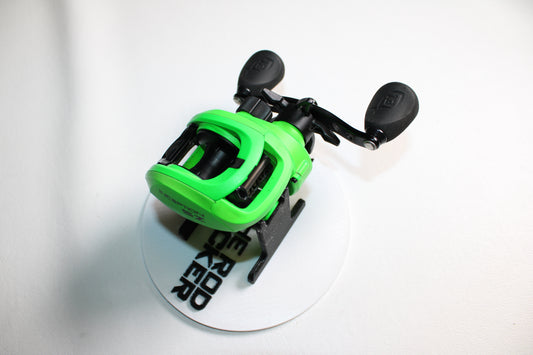 A 13 Fishing Inception Sport Z 7.3:1 gear ratio used casting reel in bright green with black handles sits on a white surface with partial black text, shown against a white background. Brand: 13 Fishing. Condition: Very good.
