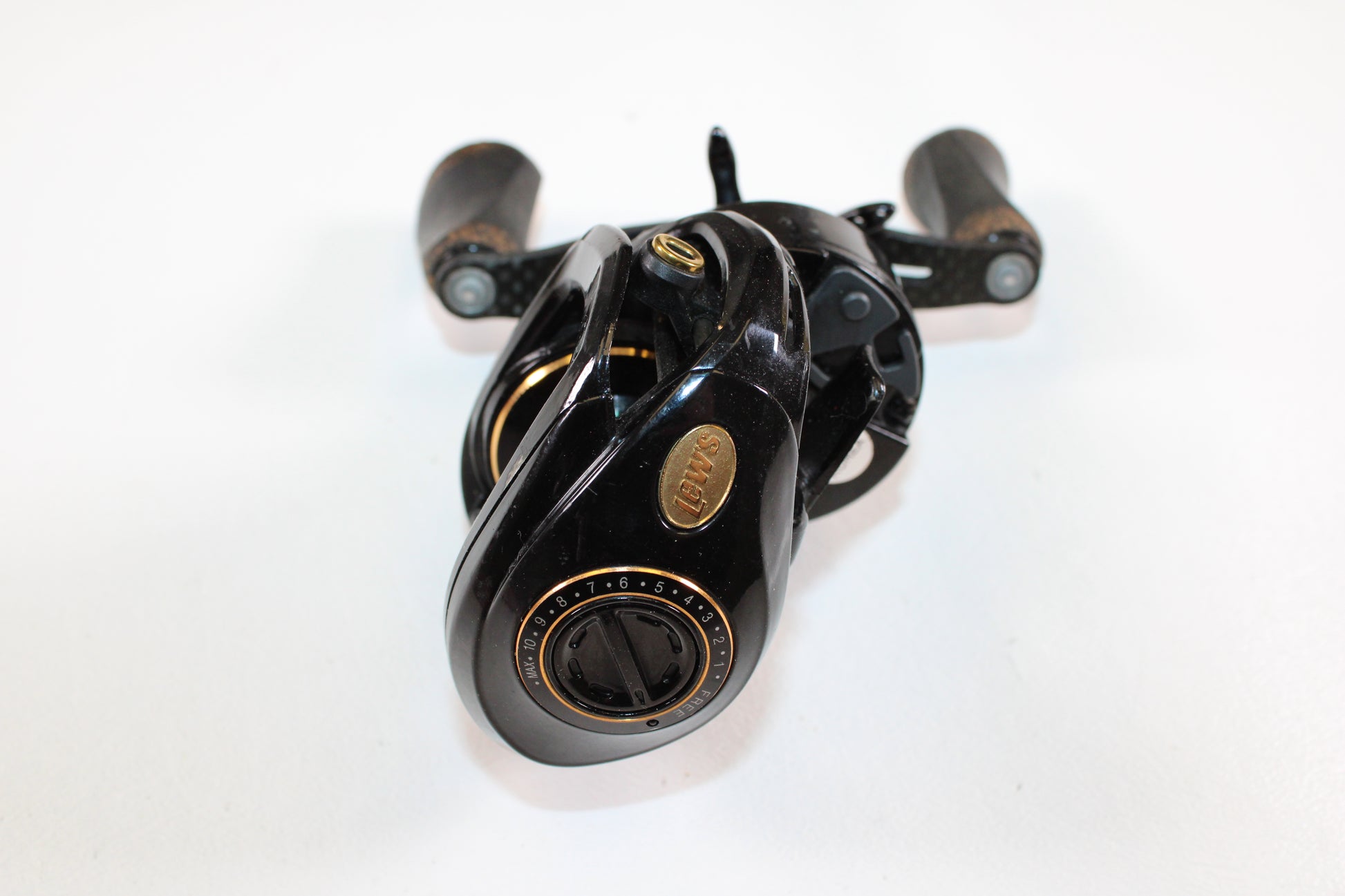 A Lew's Lite MgF LFS 7.5:1 LH Used Casting Reel in good condition—with black finish, gold accents, and wooden handle grips—is shown on a white background, ideal for Rod and Reel Trade-In or assessing Used Gear Condition.