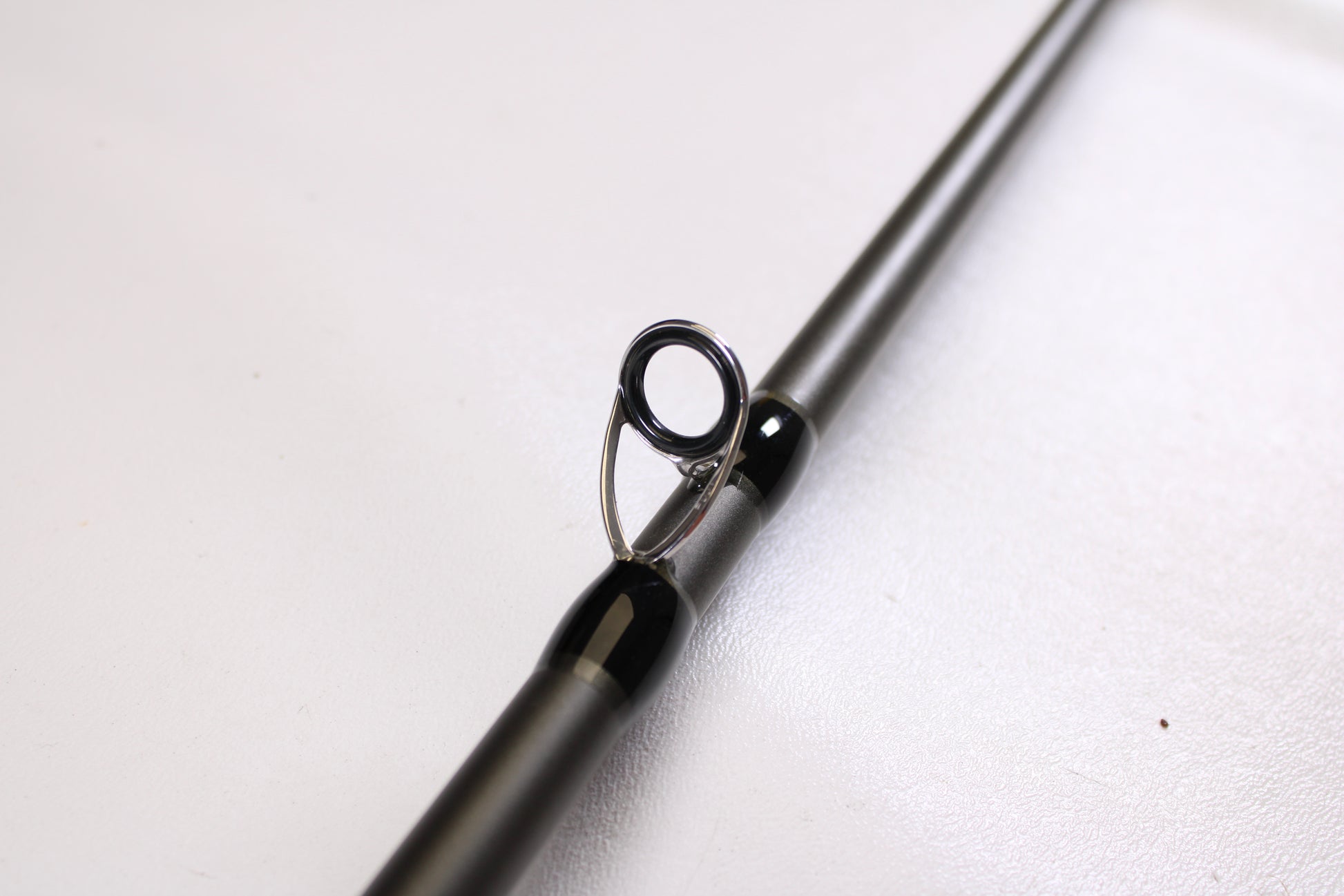 Close-up of a Douglas XMatrix DXC 807F 8'0" Extra Heavy Used Casting Rod in excellent condition, showing a single metal guide loop on the shaft—ideal for upgrading through our rod and reel trade-in program. Smooth, light background.