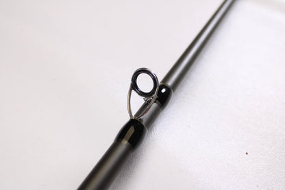 Close-up of a Douglas XMatrix DXC 807F 8'0" Extra Heavy Used Casting Rod in excellent condition, showing a single metal guide loop on the shaft—ideal for upgrading through our rod and reel trade-in program. Smooth, light background.