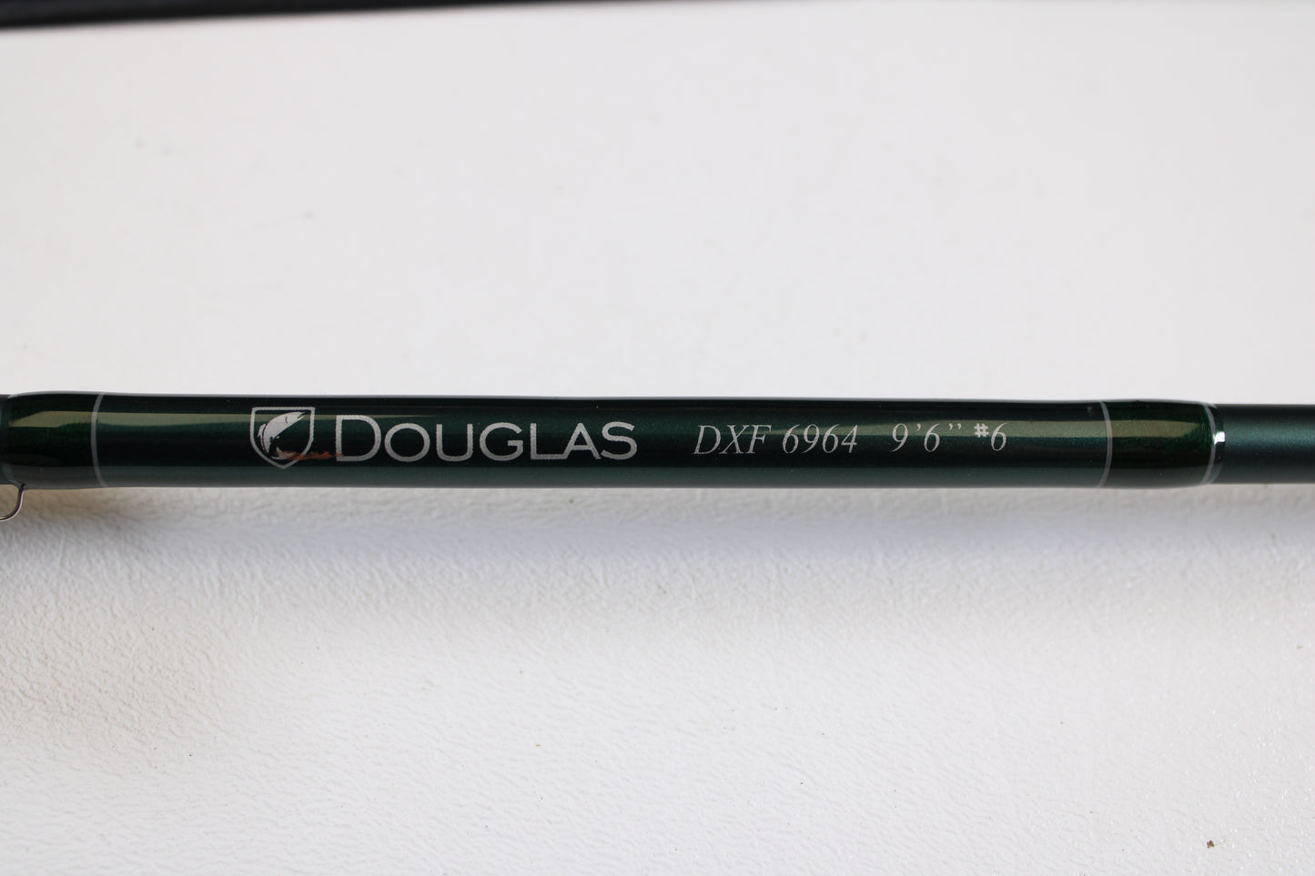A close-up of a Douglas DXF Gen 1 6964 9'6" 6wt 4pc Used Fly Rod in excellent condition, shown on a white surface—ideal for those interested in our rod and reel trade-in program for store credit.
