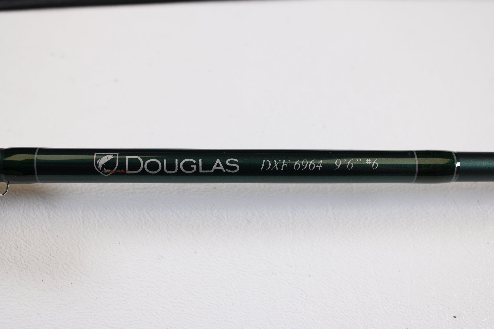 A close-up of a Douglas DXF Gen 1 6964 9'6" 6wt 4pc Used Fly Rod in excellent condition, shown on a white surface—ideal for those interested in our rod and reel trade-in program for store credit.