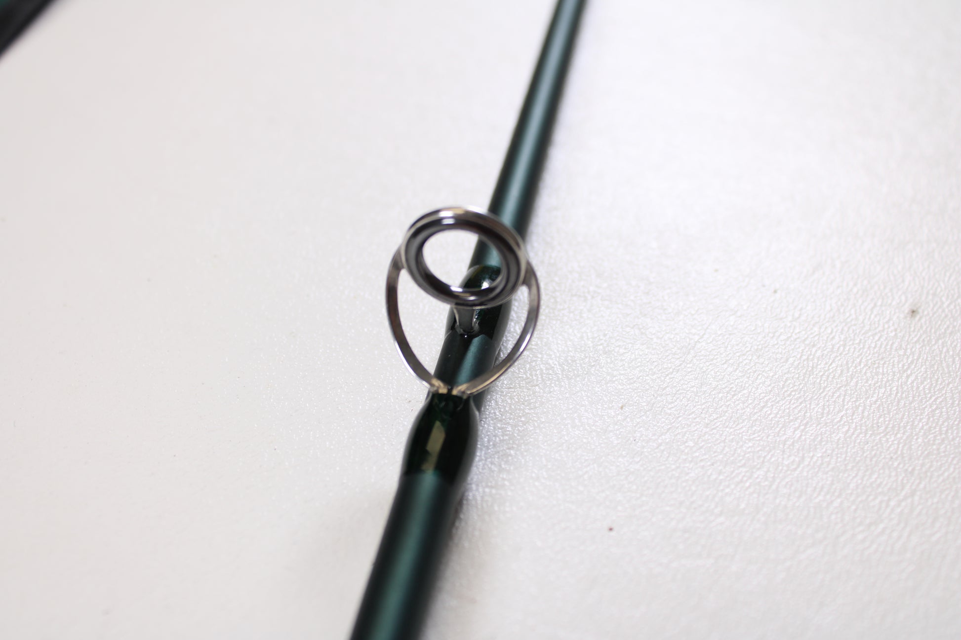 Close-up of the Douglas DXF Gen 1 6964 9'6" 6wt 4pc Used Fly Rod in excellent condition, highlighting its metal guide on a green rod. Ideal for those exploring our rod and reel trade-in program.