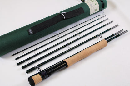 A disassembled Sage Orvis Frequent Flyer 908 9'0" 8wt 7pc fly rod in excellent condition is displayed beside a green carrying case—ideal for upgrading with our Rod and Reel Trade-In Program and earning store credit on used gear.