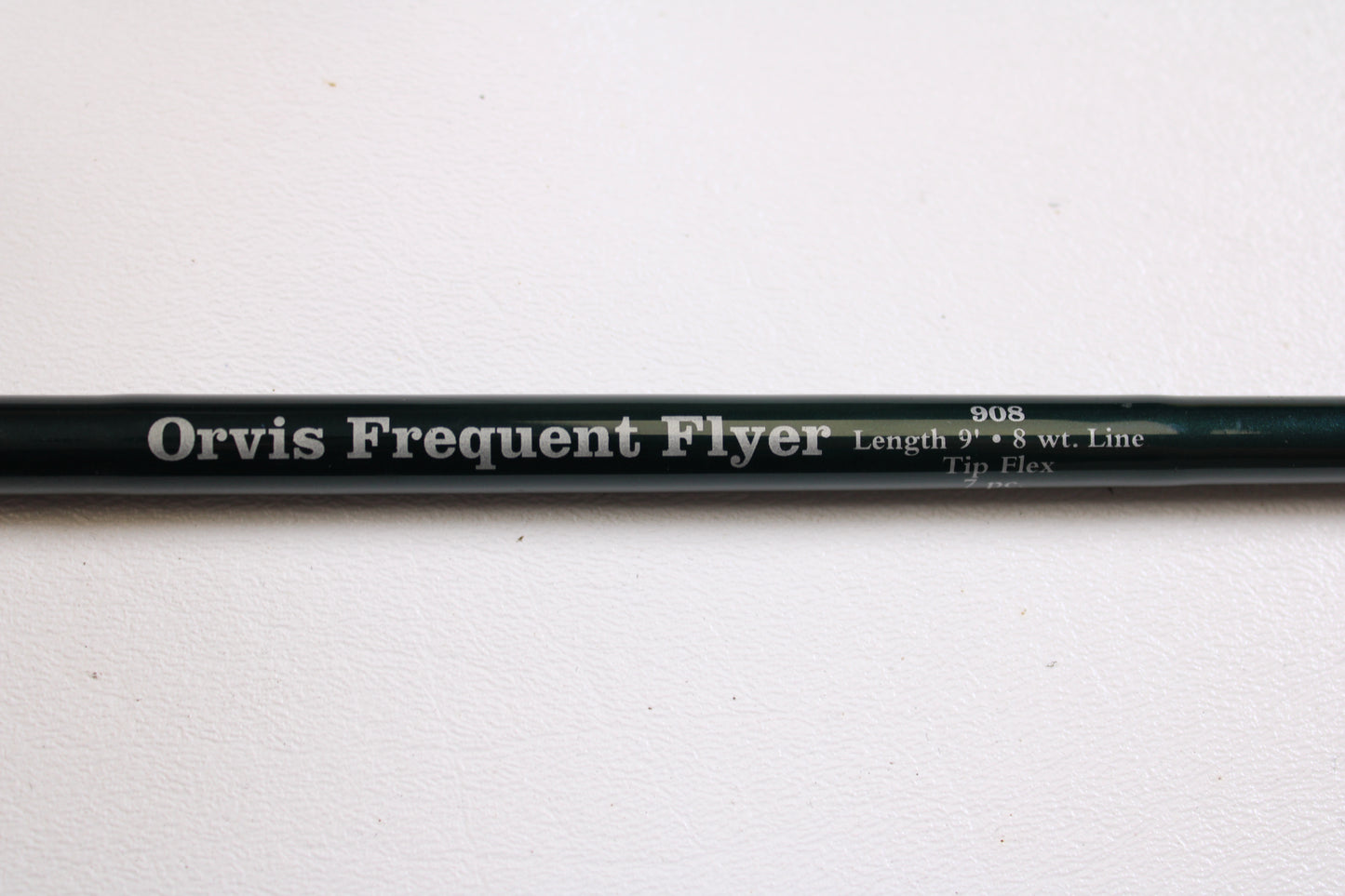 A close-up of a Sage Orvis Frequent Flyer 908 9'0" 8wt 7pc used fly rod in excellent condition, resting on a white surface—ideal for those interested in pre-owned gear or the Rod and Reel Trade-In Program.