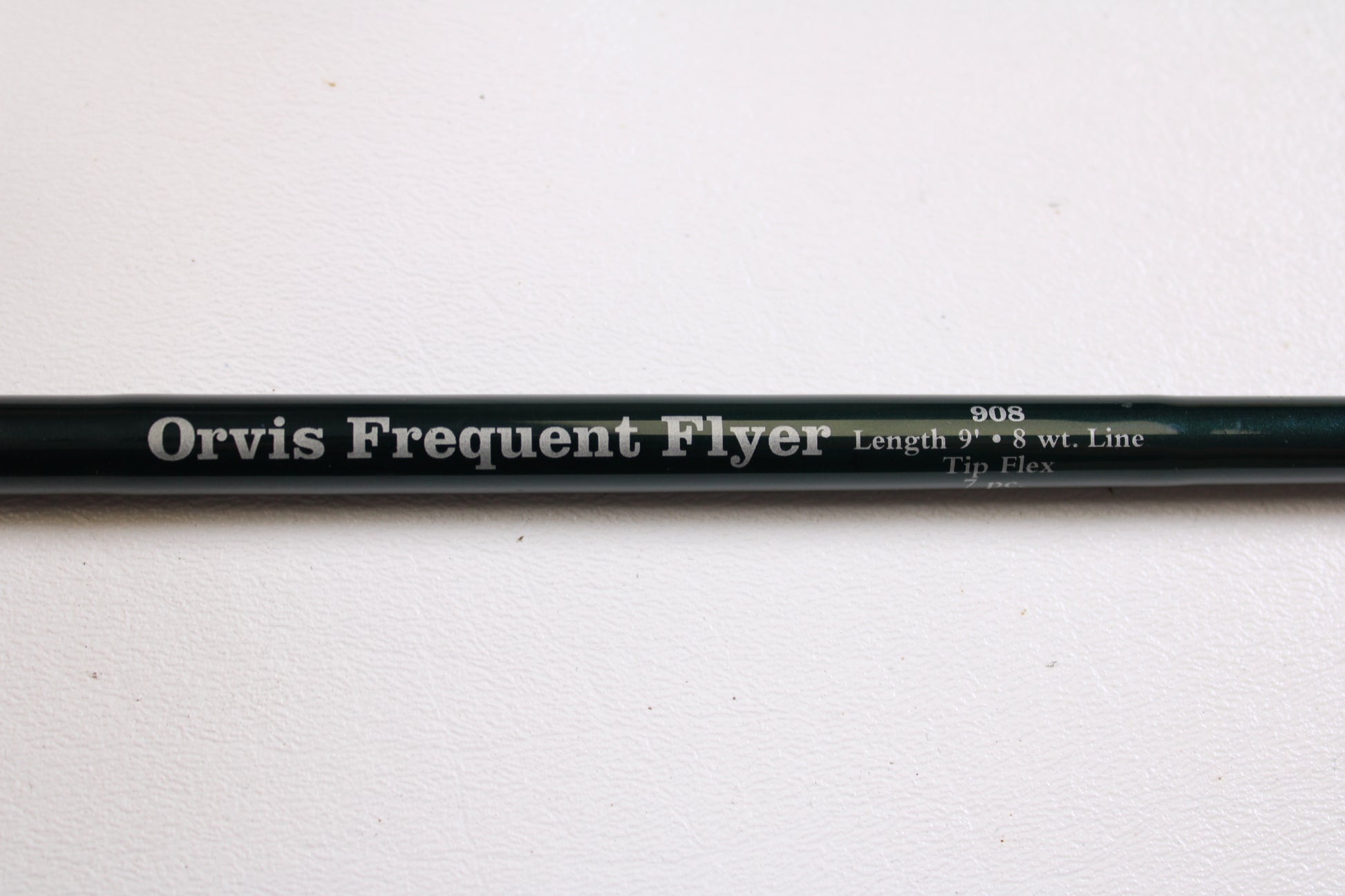 A close-up of a Sage Orvis Frequent Flyer 908 9'0" 8wt 7pc used fly rod in excellent condition, resting on a white surface—ideal for those interested in pre-owned gear or the Rod and Reel Trade-In Program.