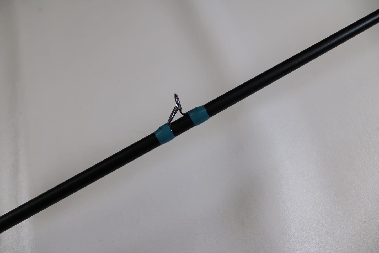 A close-up of the G. Loomis NRX+ 903C MBR Used Casting Rod in excellent condition, featuring a black blank, silver guide ring, and teal thread wrap—eligible for our Rod and Reel Trade-In Program to earn store credit for used gear.